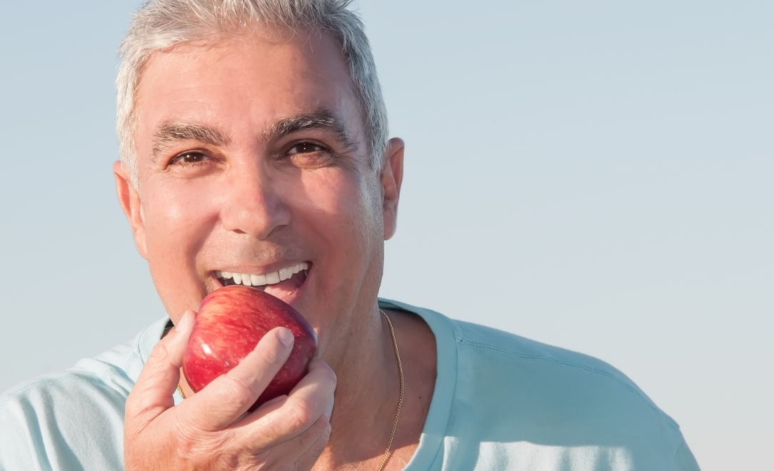 happy dental implant patient biting an apple